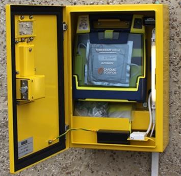 An open yellow defibrillator box with a defibrillator inside. 